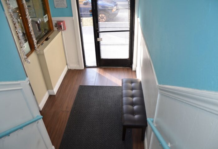 Hotel Sunrise gay-friendly hotel entrance. Interior view with bench, mat, and door. Travel advice for gay men. Welcoming space.