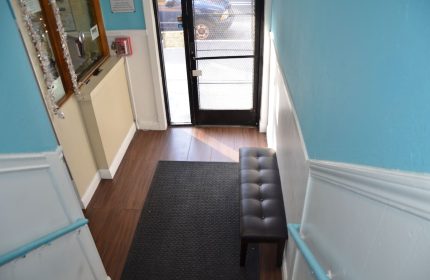 Hotel Sunrise gay-friendly hotel entrance. Interior view with bench, mat, and door. Travel advice for gay men. Welcoming space.