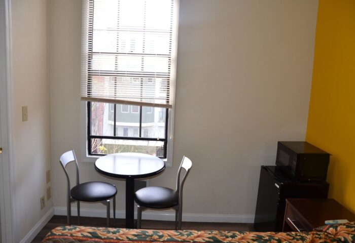 Hotel Sunrise room with table, chairs, mini-fridge, microwave. Gay-friendly hotel interior shot for gay men travel advice.