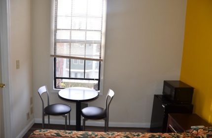 Hotel Sunrise room with table, chairs, mini-fridge, microwave. Gay-friendly hotel interior shot for gay men travel advice.