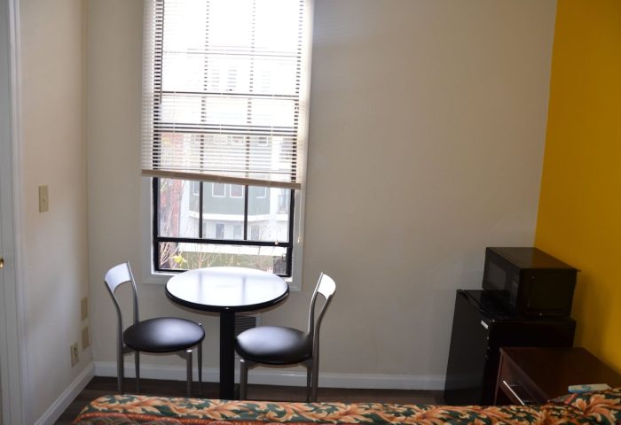 Hotel Sunrise room with table, chairs, mini-fridge, microwave. Gay-friendly hotel interior shot for gay men travel advice.