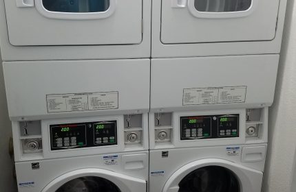 Hotel Sunrise's laundry facilities: Two stacked sets of white washing machines and dryers. A gay-friendly hotel amenity for guests' convenience.