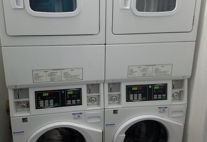 Hotel Sunrise's laundry facilities: Two stacked sets of white washing machines and dryers. A gay-friendly hotel amenity for guests' convenience.