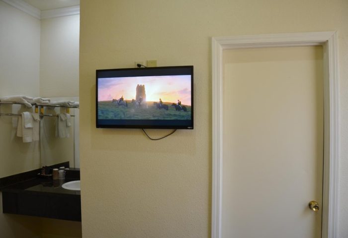 Hotel Sunrise gay-friendly room: TV showing riders on horseback, next to a door and bathroom sink. Ideal for gay men travel advice.