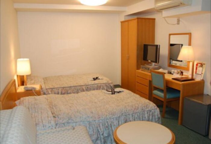 Hotel Tateshina room with two beds, desk, and TV. Gay-friendly hotel offering comfortable accommodations for gay travelers. Interior design.