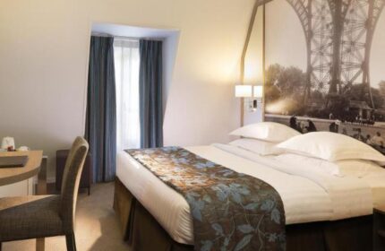 Hotel Turenne Le Marais room. Gay-friendly, pet-friendly hotel bedroom with Eiffel Tower mural. Desk, chair, bed with floral throw. Paris lodging.