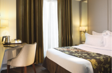 Hotel Turenne Le Marais room. Gay-friendly, pet-friendly hotel in Paris. Bed, desk, chair, and curtains. Parisian hotel room interior.
