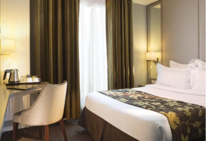 Hotel Turenne Le Marais room. Gay-friendly, pet-friendly hotel in Paris. Bed, desk, chair, and curtains. Parisian hotel room interior.