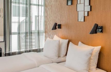 Hotel V Frederiksplein's gay-friendly room. Two beds with white linens, modern lamps, and stylish decor. A comfortable stay in Amsterdam.