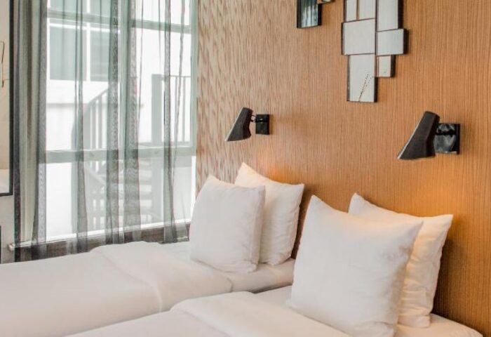 Hotel V Frederiksplein's gay-friendly room. Two beds with white linens, modern lamps, and stylish decor. A comfortable stay in Amsterdam.