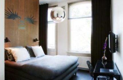 Hotel V Frederiksplein gay-friendly room. Modern design with a bed, desk, and unique wall art. Stylish Amsterdam hotel for gay travelers.