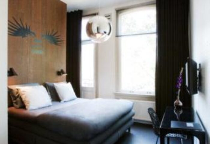 Hotel V Frederiksplein gay-friendly room. Modern design with a bed, desk, and unique wall art. Stylish Amsterdam hotel for gay travelers.