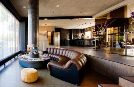 Hotel V Frederiksplein's stylish lounge. Gay-friendly hotel with modern design, brown leather sofa, and fireplace. Amsterdam travel advice.