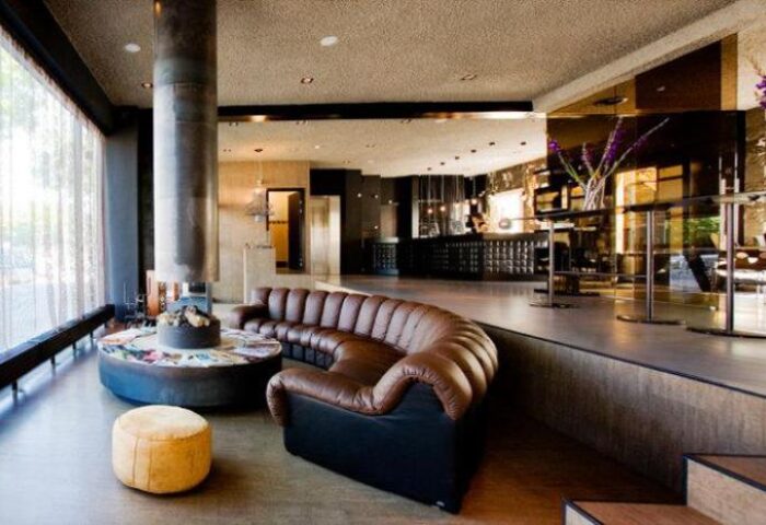 Hotel V Frederiksplein's stylish lounge. Gay-friendly hotel with modern design, brown leather sofa, and fireplace. Amsterdam travel advice.