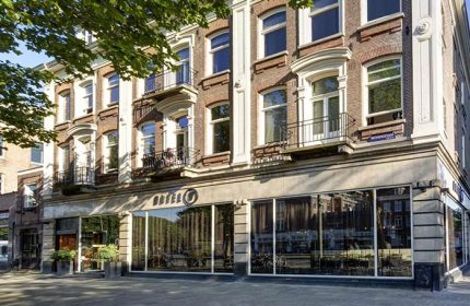 Hotel V Frederiksplein, a gay-friendly hotel in Amsterdam. Exterior view of the hotel with its brick facade and large windows.