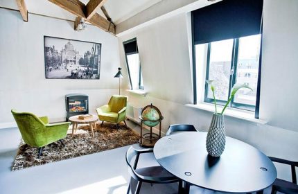 Hotel V Frederiksplein room. Gay-friendly hotel room with chairs, table, fireplace, and decor. Amsterdam lodging for gay travelers.