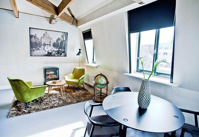 Hotel V Frederiksplein room. Gay-friendly hotel room with chairs, table, fireplace, and decor. Amsterdam lodging for gay travelers.