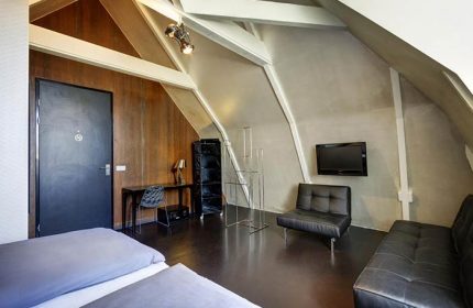 Hotel V Frederiksplein room. Gay-friendly hotel in Amsterdam with modern decor, sloped ceilings, and stylish furnishings for gay travelers.