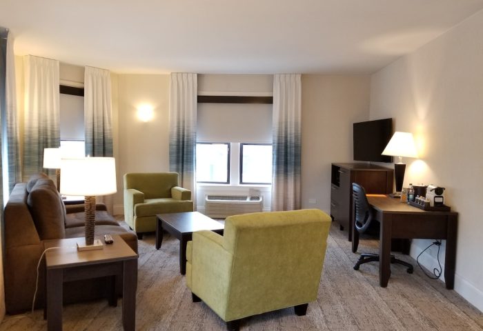 Hotel Versey Chicago Lincoln Park suite. Gay-friendly hotel room with sofa, chairs, desk, and TV. Modern design for a comfortable stay.