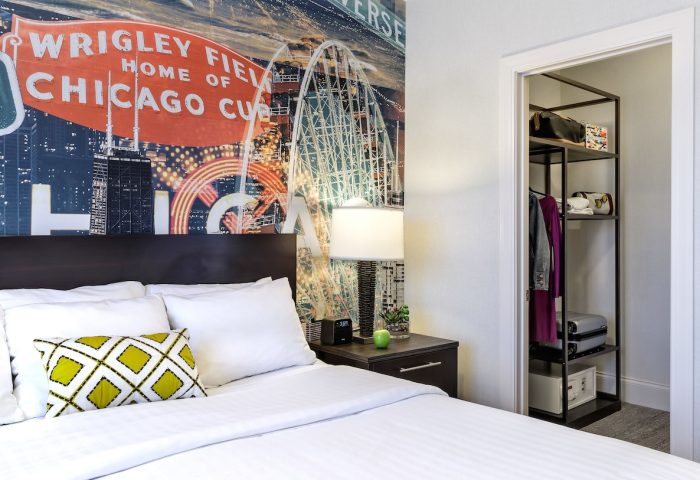 Hotel Versey Chicago Lincoln Park room. Gay-friendly hotel bed with Chicago-themed mural. Closet with shelves. Comfy, modern design.
