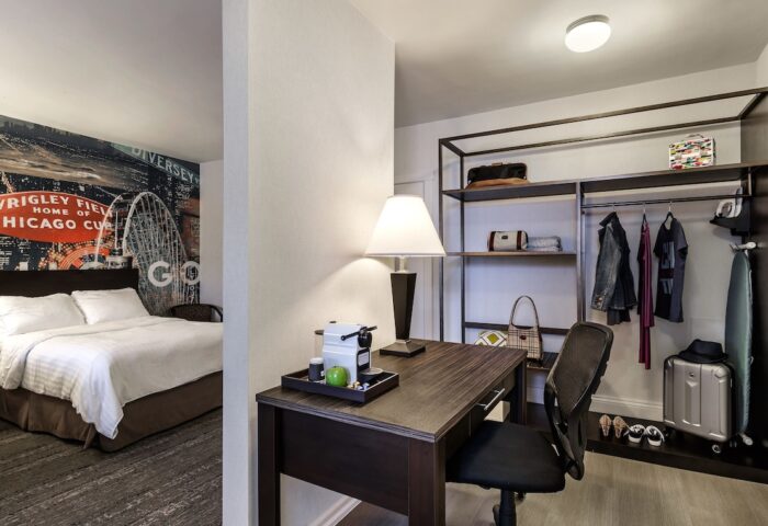 Hotel Versey Chicago Lincoln Park room with bed, desk, and closet. Gay-friendly hotel with modern design. Chicago Cubs mural on wall.