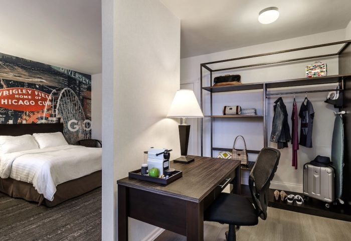 Hotel Versey Chicago Lincoln Park room with bed, desk, and closet. Gay-friendly hotel with modern design. Chicago Cubs mural on wall.