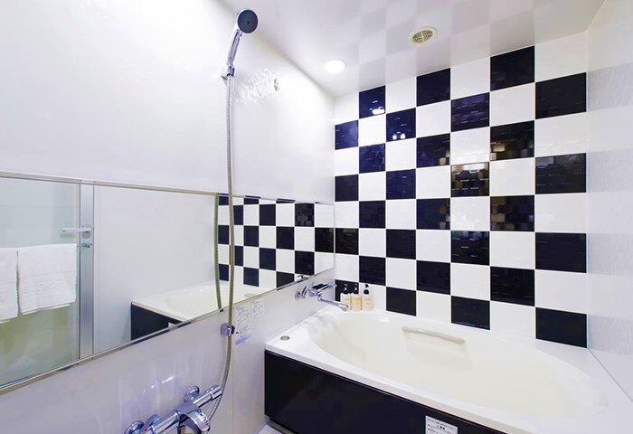 Hotel Villa Fontaine Tokyo-Shinjuku bathroom. Black & white checkered tiles, bathtub, shower, & mirror. Gay-friendly hotel for gay travelers.