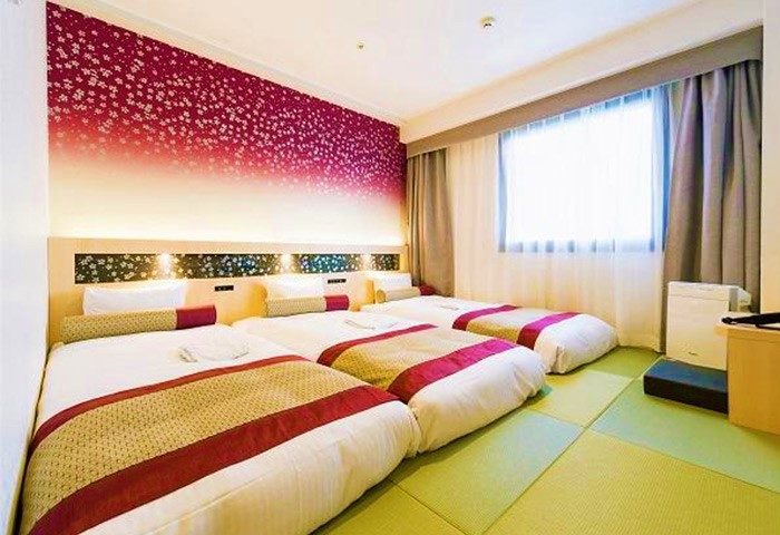 Hotel Wing International Premium Tokyo-Yotsuya: Triple room at gay-friendly hotel. Beds with red accents, tatami mats, & floral wall design.