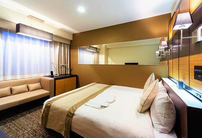 Hotel Wing International Premium Tokyo-Yotsuya room. Gay-friendly hotel featuring modern design, bed, sofa, and large mirror for LGBTQ+ travelers.