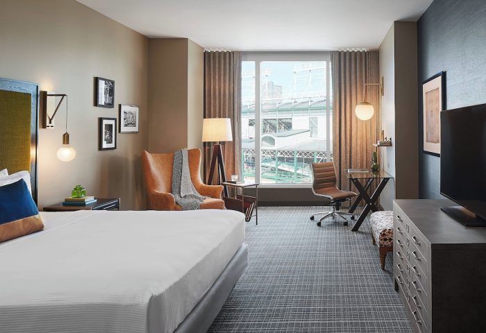 Hotel Zachary, Chicago, a Tribute Portfolio Hotel guest room. Gay-friendly hotel room with bed, chair, desk, and view of Wrigley Field.