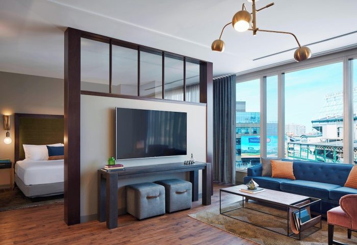 Hotel Zachary, a Tribute Portfolio Hotel, gay-friendly Chicago hotel room with a bed, TV, couch, and view of the city.