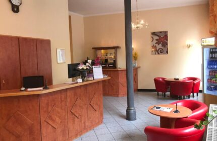 Hotel Zeil's lobby, a gay-friendly hotel. It features a reception desk, bar, and seating area with red chairs, catering to gay travelers.