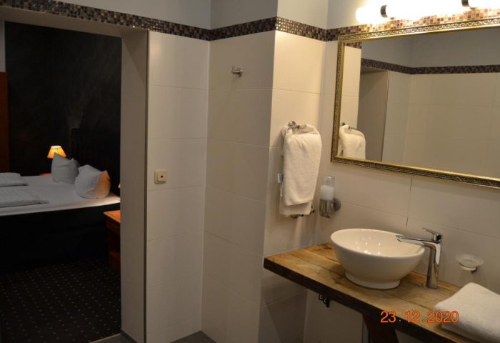 Hotel Zeil gay-friendly room. Bathroom with sink, mirror, and view into bedroom with bed. Zeil is a top destination for gay travel.