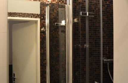Hotel Zeil gay-friendly bathroom. Shower stall with mosaic tiles, sink, and mirror. Modern design for a comfortable stay.