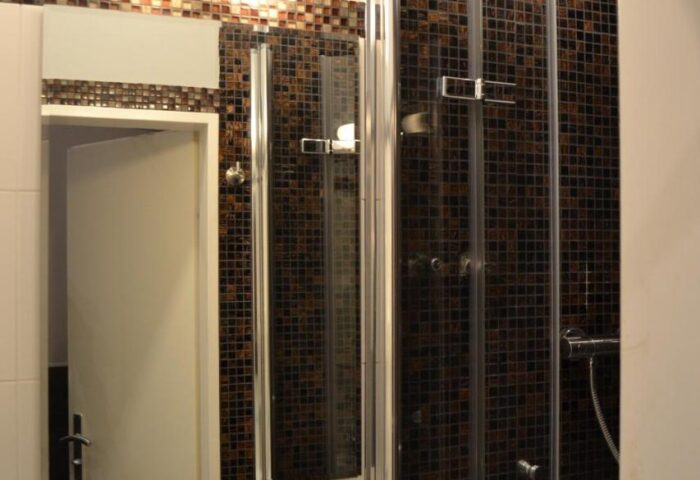 Hotel Zeil gay-friendly bathroom. Shower stall with mosaic tiles, sink, and mirror. Modern design for a comfortable stay.