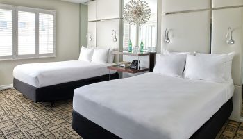 Hotel Ziggy Los Angeles gay-friendly hotel room. Two beds with white linens, modern decor, and mirrored accents. Perfect for gay travel.