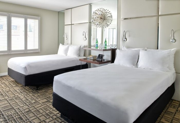 Hotel Ziggy Los Angeles gay-friendly hotel room. Two beds with white linens, modern decor, and mirrored accents. Perfect for gay travel.