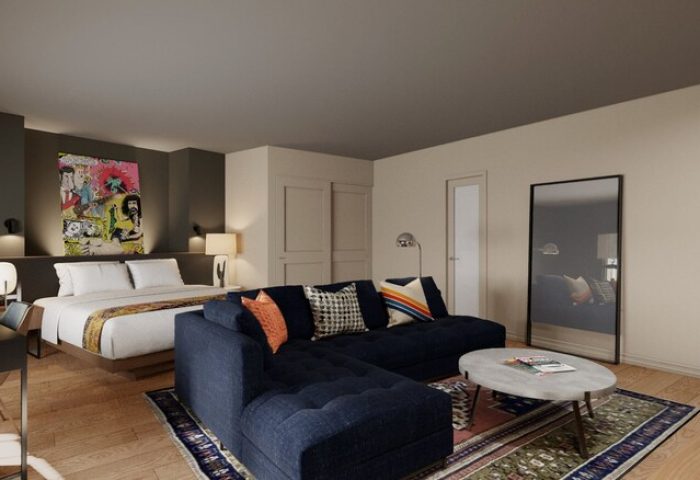 Hotel Ziggy Los Angeles gay-friendly room. A bed with white linens, a blue sectional couch, and a colorful art piece above the bed.