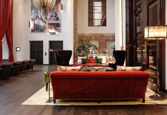 Hotel Zoo Berlin's gay-friendly lobby with red sofas, high ceilings, and art. Pet-friendly design with comfortable seating. Stylish, welcoming space.