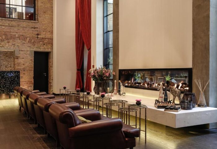 Hotel Zoo Berlin's chic lounge area. Leather chairs, small tables, and a modern fireplace create a stylish, pet-friendly, gay-friendly hotel space.