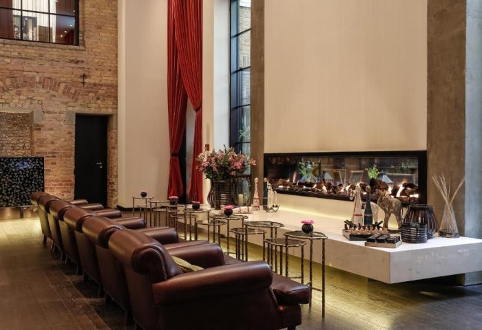 Hotel Zoo Berlin's chic lounge area. Leather chairs, small tables, and a modern fireplace create a stylish, pet-friendly, gay-friendly hotel space.
