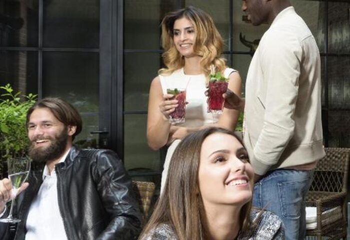 People enjoying cocktails at Hotel Zoo Berlin, a gay-friendly, pet-friendly hotel. Diverse group socializing in a stylish outdoor setting.