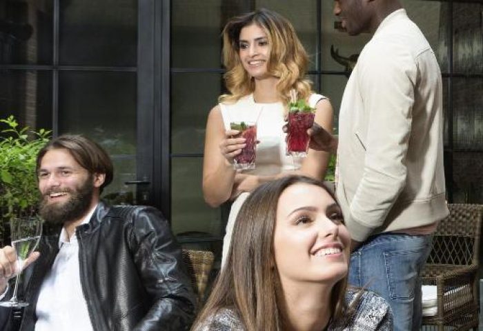 People enjoying cocktails at Hotel Zoo Berlin, a gay-friendly, pet-friendly hotel. Diverse group socializing in a stylish outdoor setting.