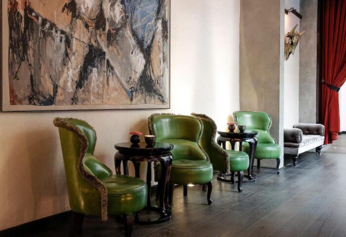 Hotel Zoo Berlin seating area. Green leather chairs, dark wood tables, & modern art create a stylish, pet-friendly, gay-friendly hotel space.