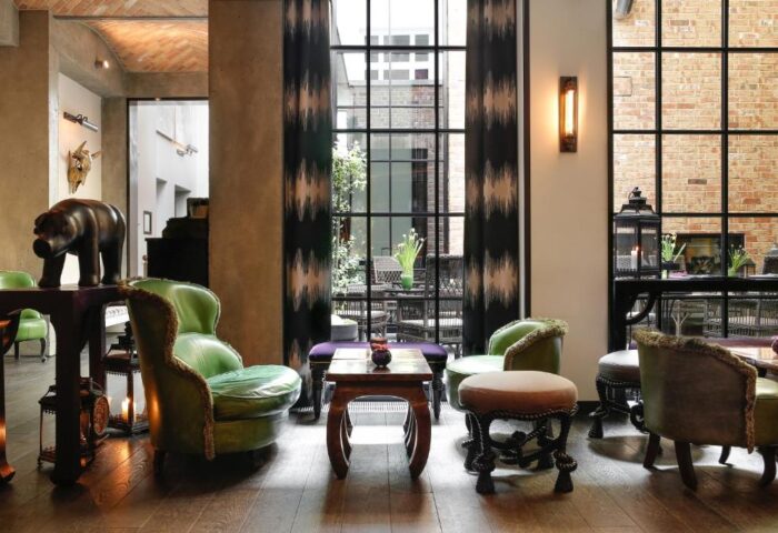 Hotel Zoo Berlin's pet-friendly, gay-friendly interior. Green chairs, wooden floors, and a large window create a stylish, welcoming space.
