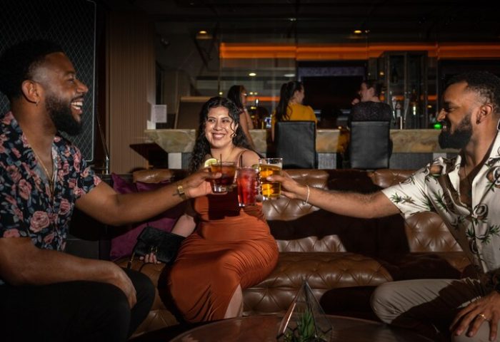 Hotel Zoso gay-friendly hotel: Three friends toasting drinks in a bar. Hotel Zoso is a great place for gay men to travel and have fun.