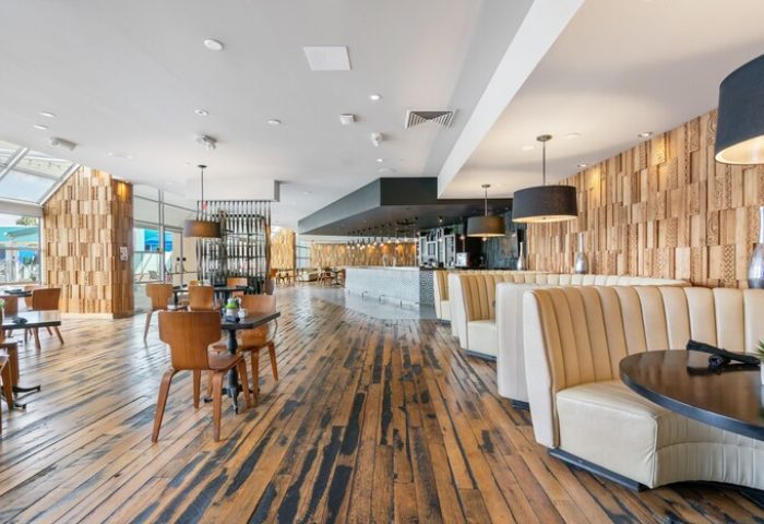Hotel Zoso's gay-friendly restaurant interior. Wood floors, booths, tables, and decorative wood walls create a stylish dining space.