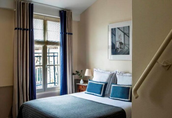 Hotel de la Place du Louvre gay-friendly room. Pet-friendly hotel room with double bed, blue accents, and natural light. Paris gay travel.