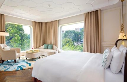 Hôtel des Arts Saigon, MGallery Collection room. Gay-friendly hotel with bed, chair, sofa, & city view. Luxury gay travel in Vietnam.
