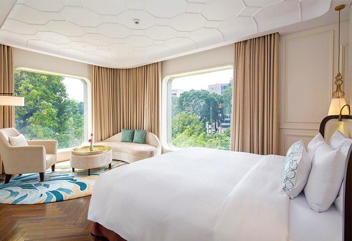 Hôtel des Arts Saigon, MGallery Collection room. Gay-friendly hotel with bed, chair, sofa, & city view. Luxury gay travel in Vietnam.